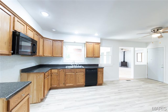1575 County Road 3290, Salem, MO 65560 - kitchen featuring black appliances, a sink, a wood stove, light wood-style floors, and a ceiling fan