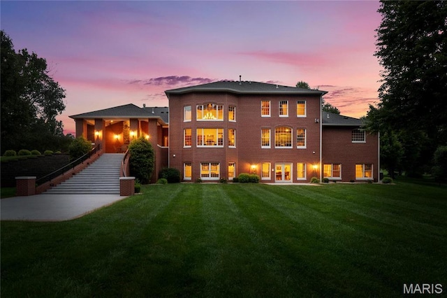 back of property at dusk featuring a yard