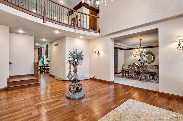 foyer entrance with a chandelier, wood finished floors, baseboards, stairway, and a high ceiling