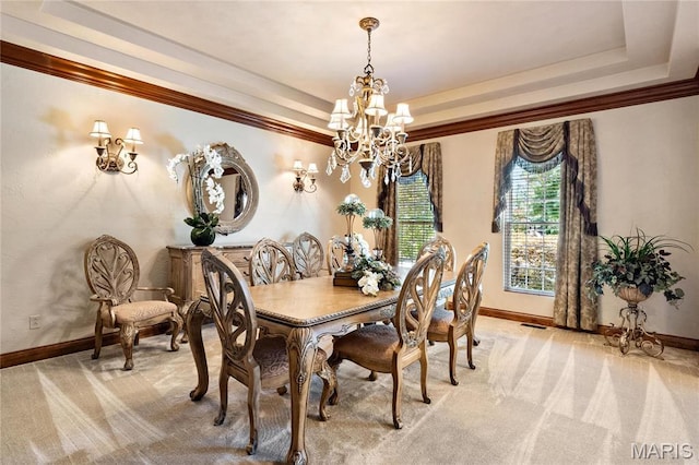 dining room featuring a chandelier, light colored carpet, a raised ceiling, baseboards, and crown molding