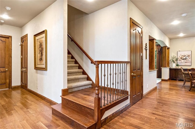 hallway featuring wood finished floors, stairs, and baseboards