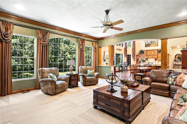 living room featuring ceiling fan, healthy amount of natural light, crown molding, light carpet, and arched walkways