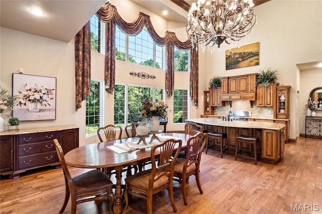 dining area featuring a towering ceiling, light wood-style floors, and a chandelier