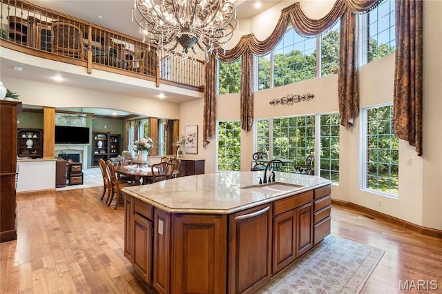 kitchen featuring a sink, light wood-style floors, brown cabinets, a high ceiling, and plenty of natural light