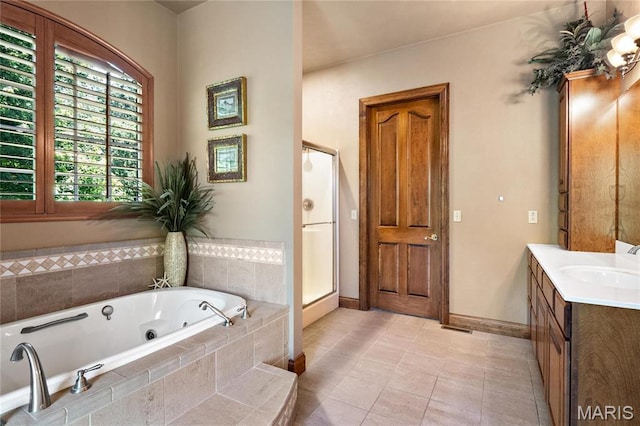 full bath featuring vanity, a jetted tub, baseboards, and tile patterned flooring