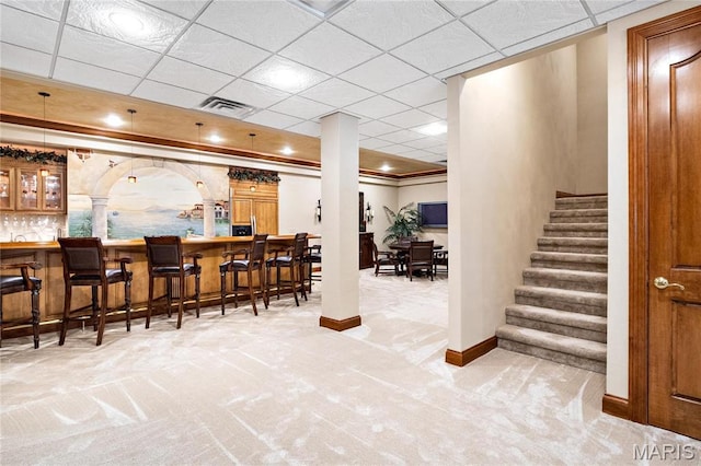 indoor dry bar with baseboards, carpet flooring, ornate columns, stairs, and ornamental molding