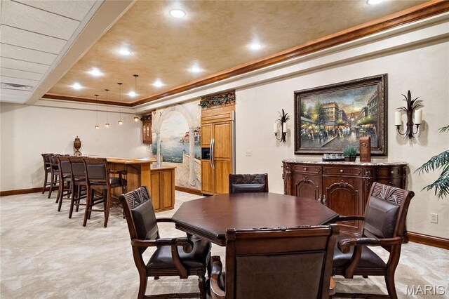 dining room with baseboards, wet bar, crown molding, a raised ceiling, and recessed lighting