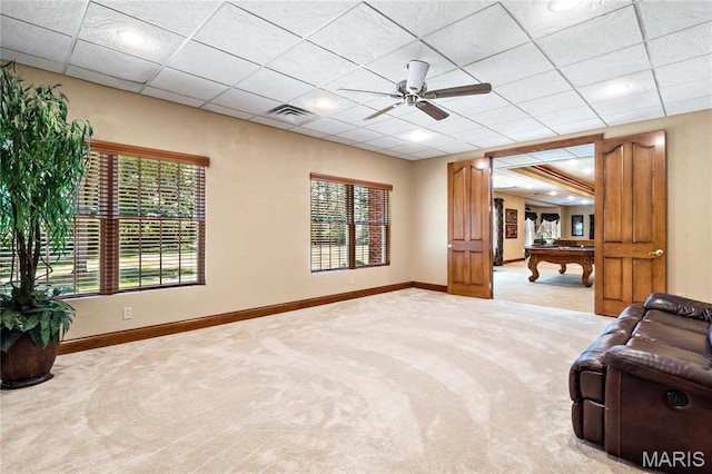 living room featuring light carpet, baseboards, ceiling fan, and a drop ceiling