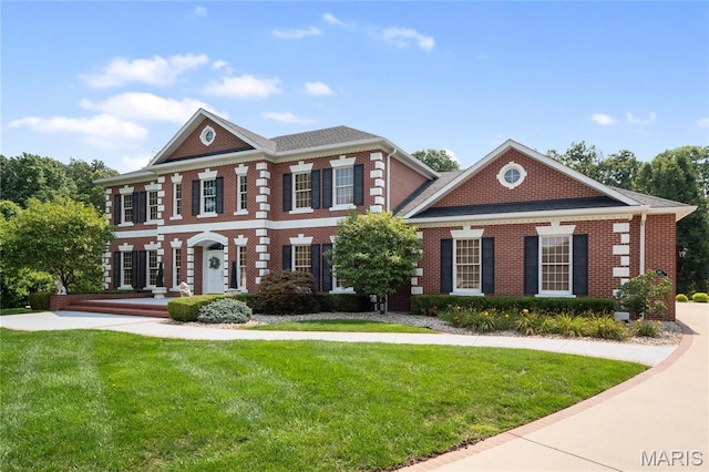 georgian-style home featuring a front yard and brick siding