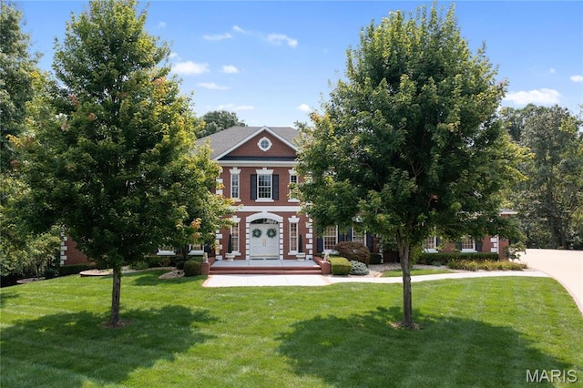 colonial inspired home with a front yard, a porch, and brick siding
