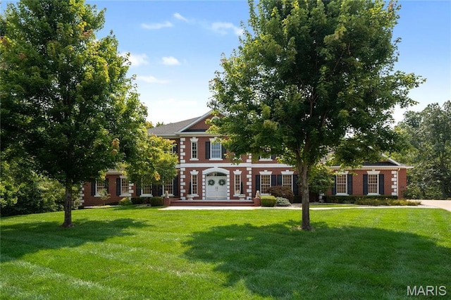 colonial-style house featuring a front yard and brick siding