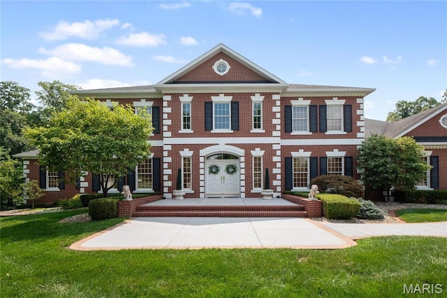 colonial-style house featuring a front yard and brick siding