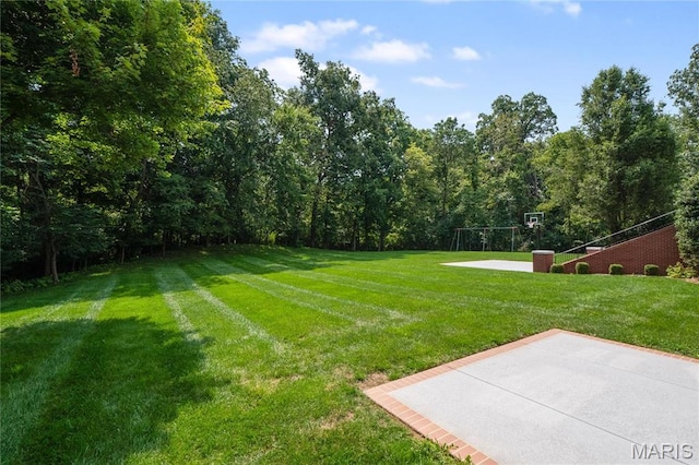 view of green lawn featuring basketball court
