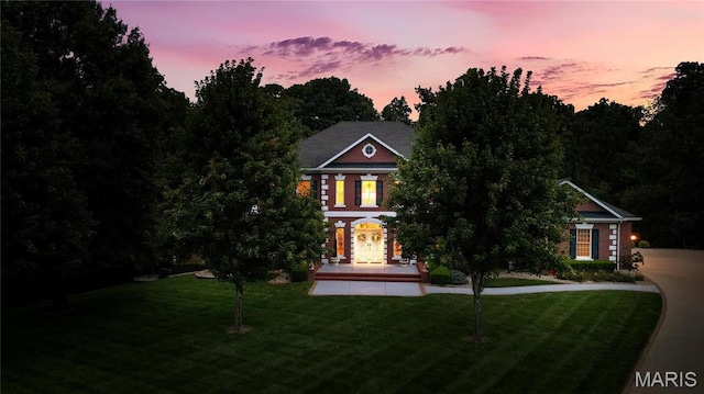 colonial-style house with a yard and covered porch