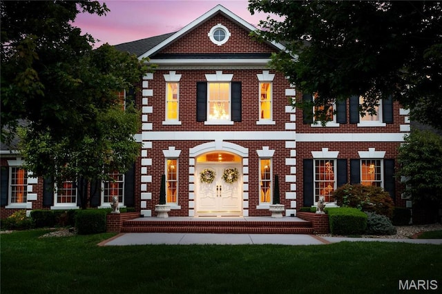 view of front facade featuring brick siding and a lawn