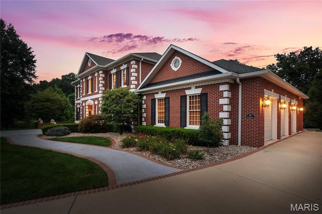 view of property exterior with brick siding, an attached garage, and driveway