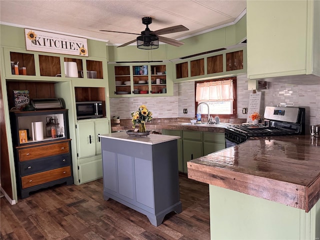 kitchen featuring stainless steel gas range oven, green cabinets, a center island, a ceiling fan, and decorative backsplash