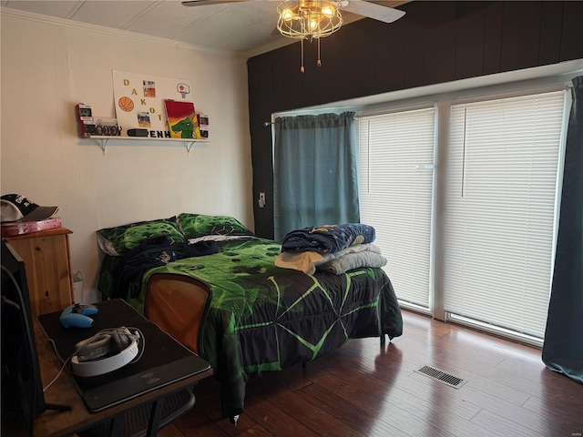 bedroom with wood finished floors, ornamental molding, and a ceiling fan