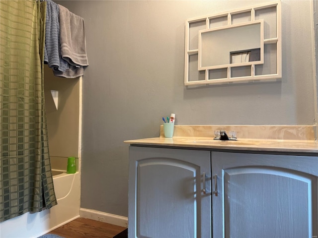bathroom featuring wood finished floors, vanity, bathtub / shower combination, and baseboards