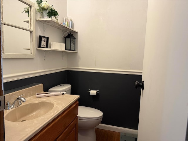 bathroom featuring toilet, vanity, and wood finished floors