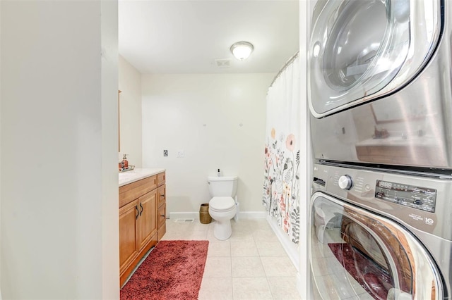 4561 Laclede Ave Unit B, Saint Louis, MO 63108 - bathroom featuring stacked washer and clothes dryer, toilet, tile patterned floors, vanity, and baseboards