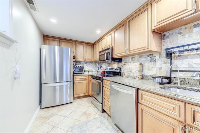 4561 Laclede Ave Unit B, Saint Louis, MO 63108 - kitchen with appliances with stainless steel finishes, backsplash, light stone counters, a sink, and light tile patterned floors