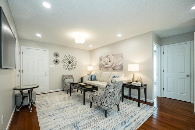 living area with baseboards, wood finished floors, recessed lighting, and a textured ceiling