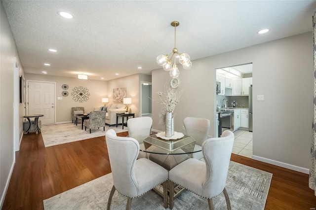 dining room with light wood-style flooring, recessed lighting, baseboards, and a textured ceiling