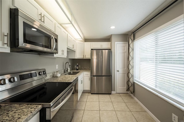 kitchen featuring appliances with stainless steel finishes, a sink, white cabinetry, healthy amount of natural light, and recessed lighting