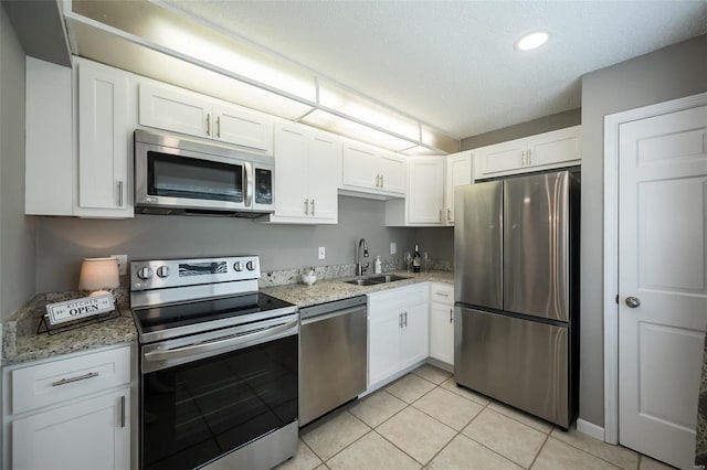 kitchen featuring appliances with stainless steel finishes, a sink, white cabinetry, light stone counters, and recessed lighting