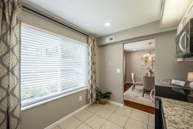 dining area featuring plenty of natural light, light tile patterned flooring, recessed lighting, a chandelier, and a textured ceiling