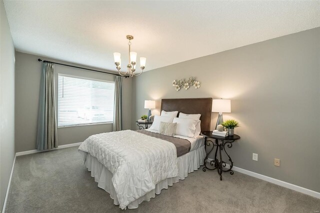 bedroom with a chandelier, light colored carpet, and baseboards