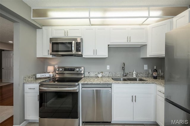 942 Guelbreth Ln Unit 112, Saint Louis, MO 63141 - kitchen featuring appliances with stainless steel finishes, white cabinetry, light stone countertops, and light wood-type flooring