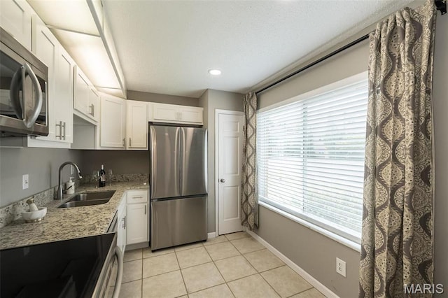 942 Guelbreth Ln Unit 112, Saint Louis, MO 63141 - kitchen with appliances with stainless steel finishes, white cabinetry, light tile patterned floors, light stone counters, and a textured ceiling