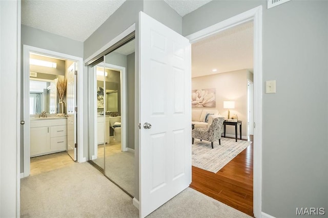942 Guelbreth Ln Unit 112, Saint Louis, MO 63141 - hall featuring light colored carpet, a textured ceiling, and light wood-style floors