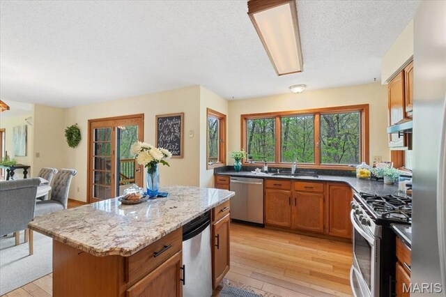 1346 Forest Splendor Trl, Wildwood, MO 63021 - kitchen featuring stainless steel appliances, a sink, light wood-style flooring, a center island, and a textured ceiling