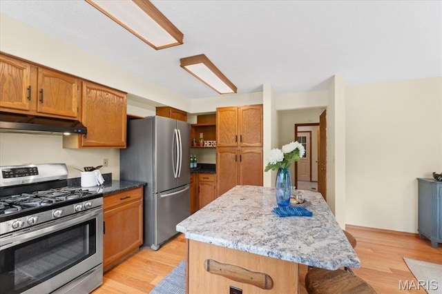 1346 Forest Splendor Trl, Wildwood, MO 63021 - kitchen featuring appliances with stainless steel finishes, under cabinet range hood, open shelves, a center island, and light wood finished floors