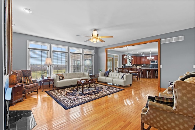 living area with a chandelier, hardwood / wood-style floors, healthy amount of natural light, and ceiling fan