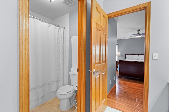ensuite bathroom with toilet, a ceiling fan, wood finished floors, and a shower with shower curtain