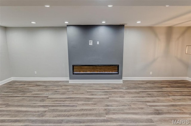 below grade area with wood finished floors, a fireplace, baseboards, and recessed lighting