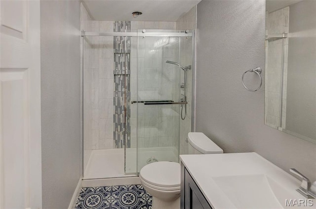 full bath with toilet, a shower stall, vanity, tile patterned floors, and a textured wall