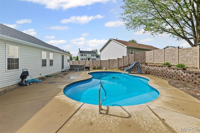 view of swimming pool with a water slide, a fenced backyard, and a patio
