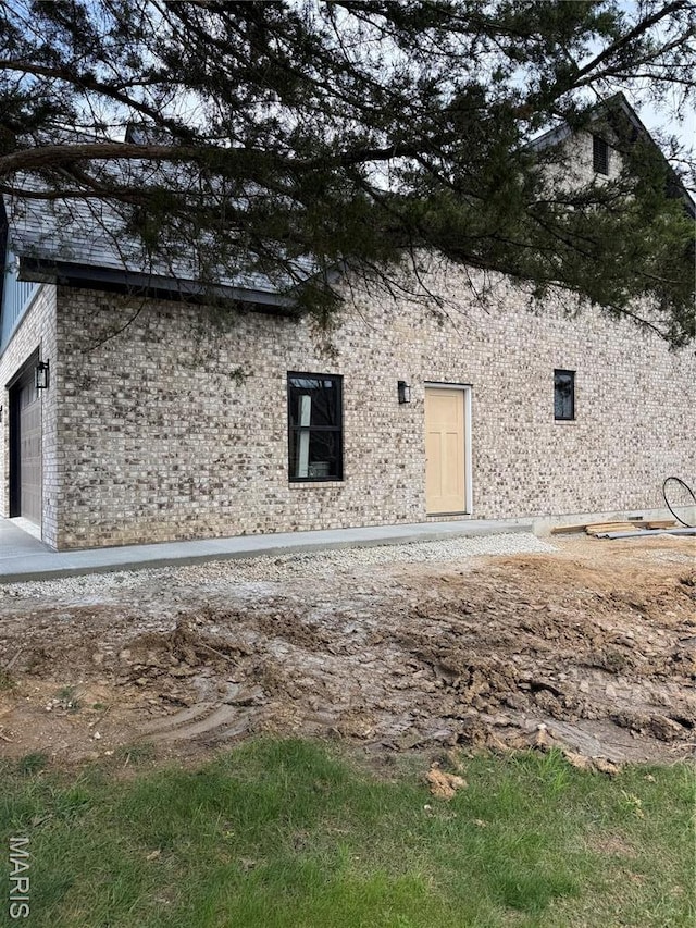 back of house with brick siding and a garage
