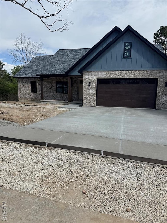 view of front of home featuring concrete driveway, a garage, brick siding, board and batten siding, and roof with shingles