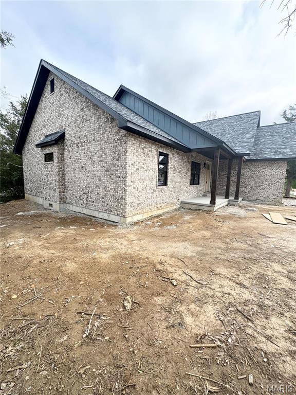 back of house with brick siding and a shingled roof
