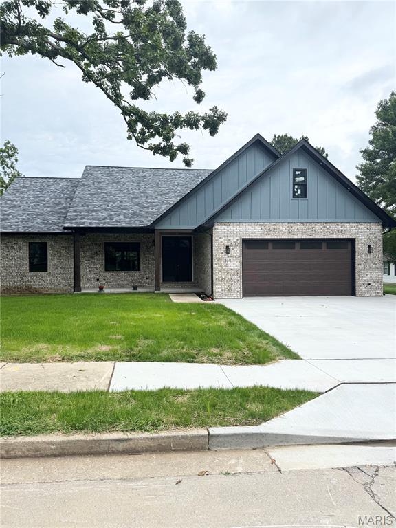 615 Scottsvale Dr, Rolla, MO 65401 - view of front of house featuring a garage, concrete driveway, a front yard, board and batten siding, and brick siding