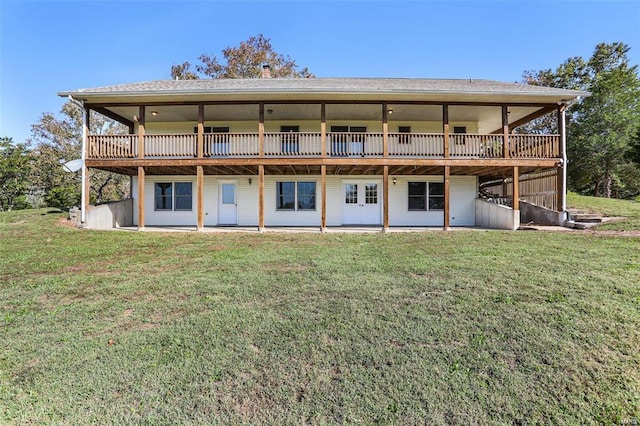 rear view of property featuring a lawn, a wooden deck, and roof with shingles