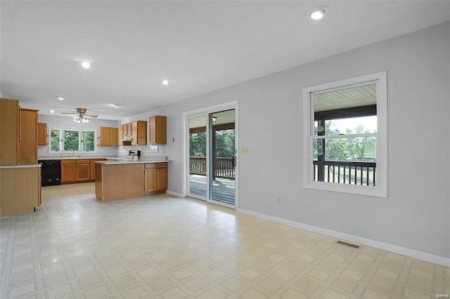 kitchen featuring dishwasher, brown cabinetry, open floor plan, healthy amount of natural light, and recessed lighting