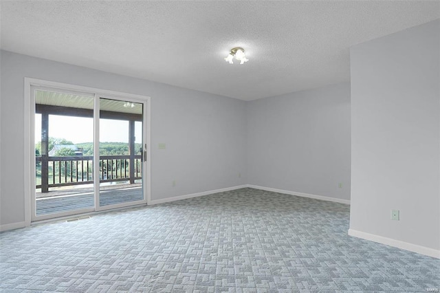 carpeted spare room featuring a textured ceiling and baseboards