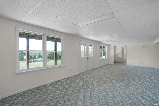 spare room with a paneled ceiling, carpet floors, and baseboards